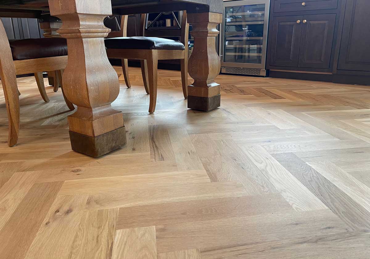 Light oak herringbone hardwood floor beneath a wooden dining table and chairs